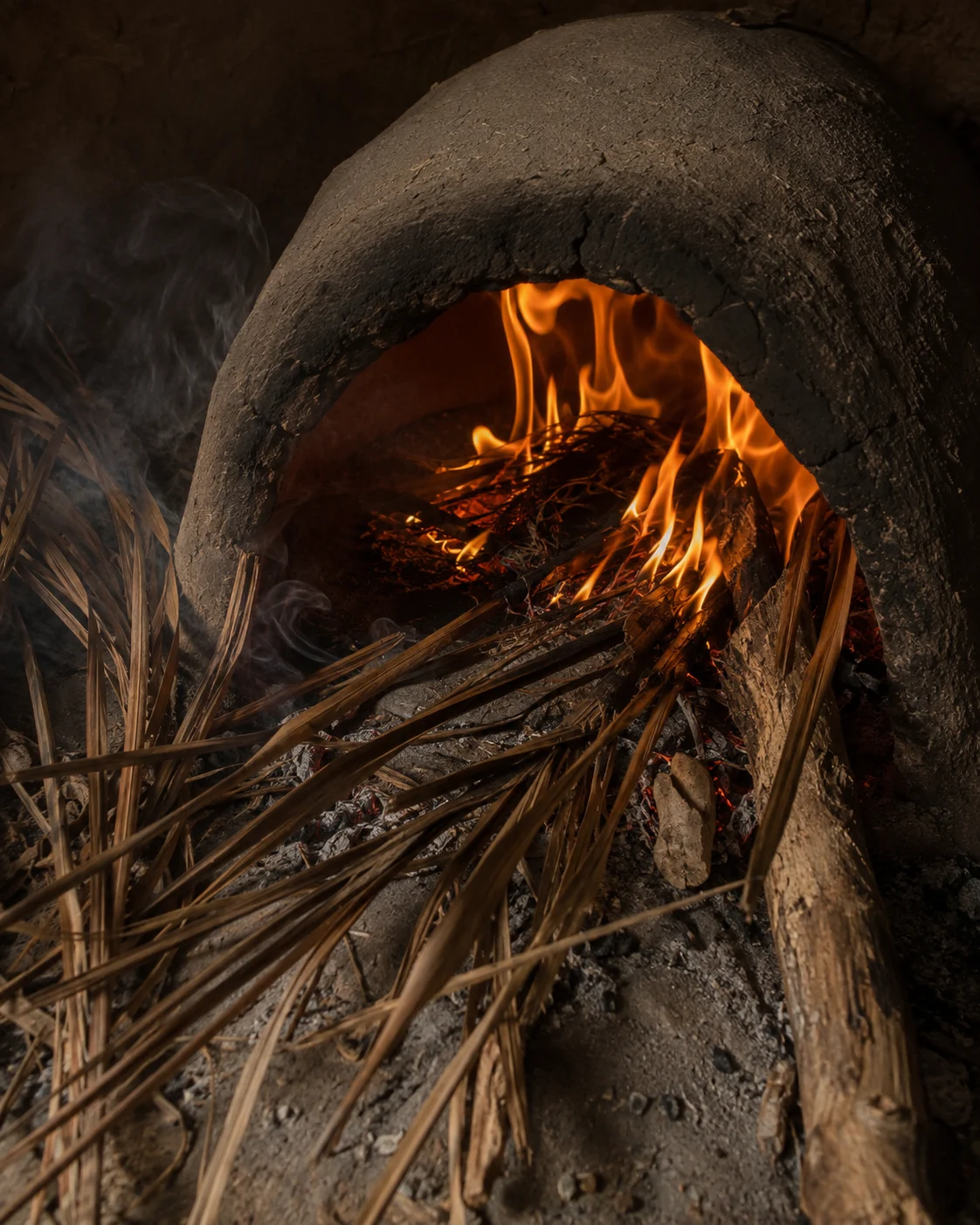 Dry palm branches feeding a traditional oven fire