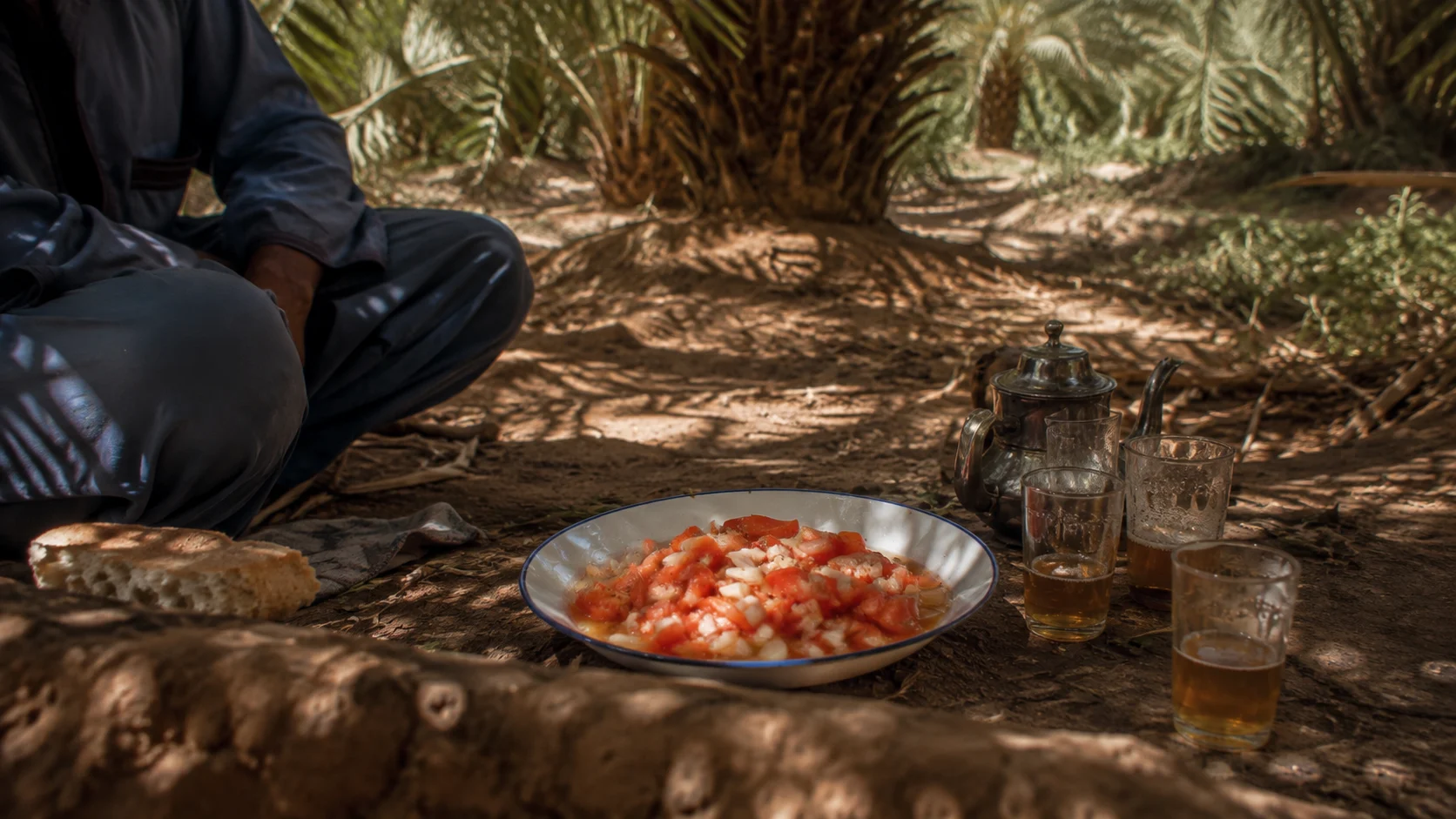A simple meal and tea shared close to the ground among palms in the Meski oasis