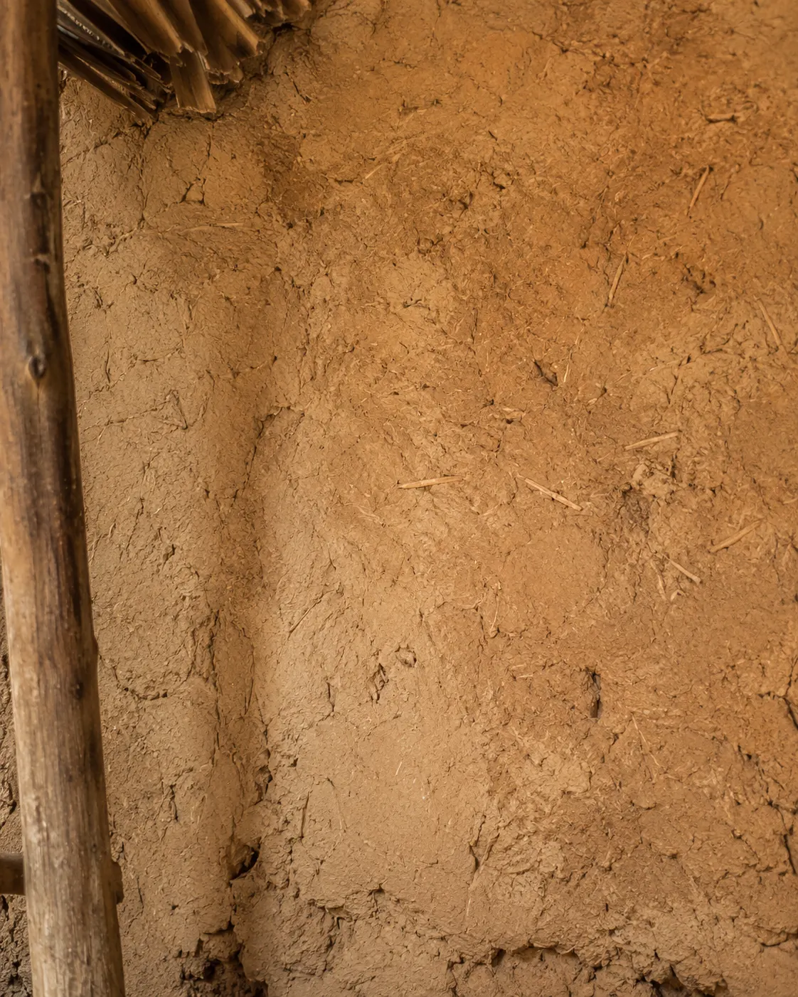 Close view of an old earth and straw wall inside a modest traditional home